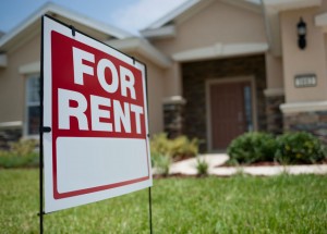 A picture of a for rent sign in front of a house.